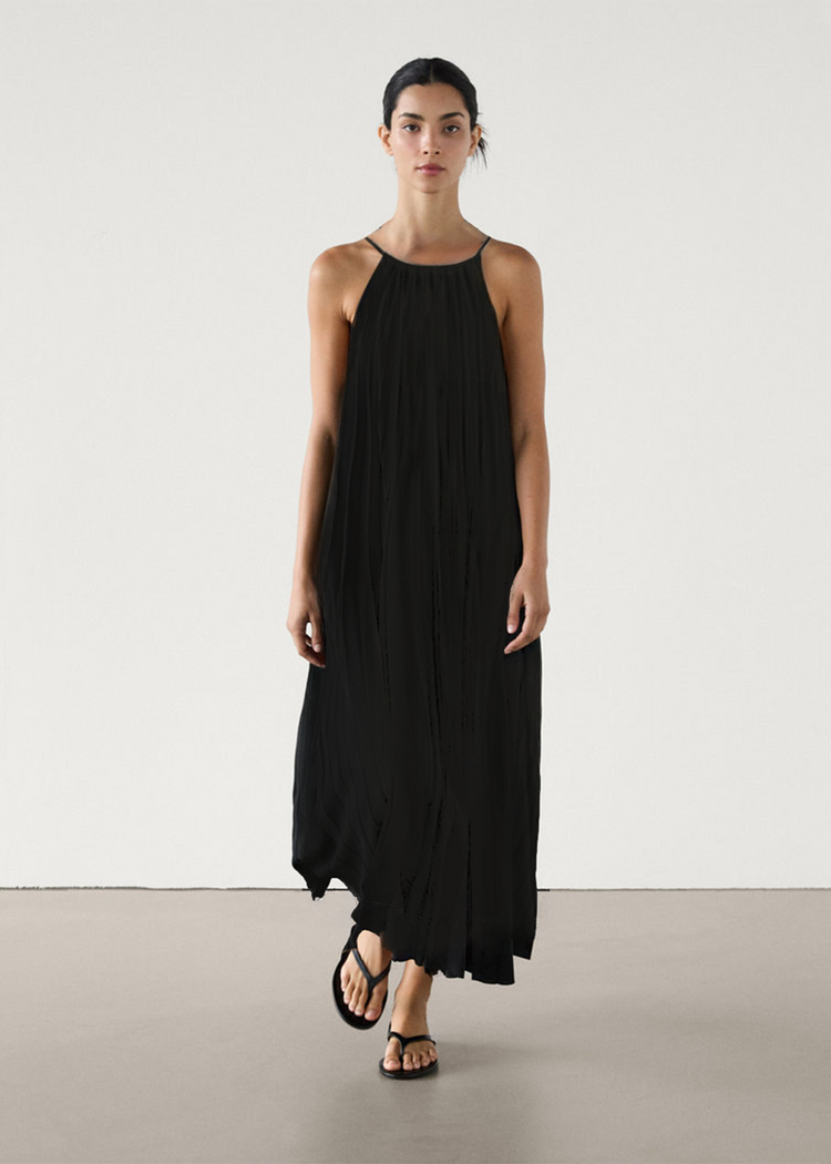 Woman wearing a black halter neck dress on a plain background