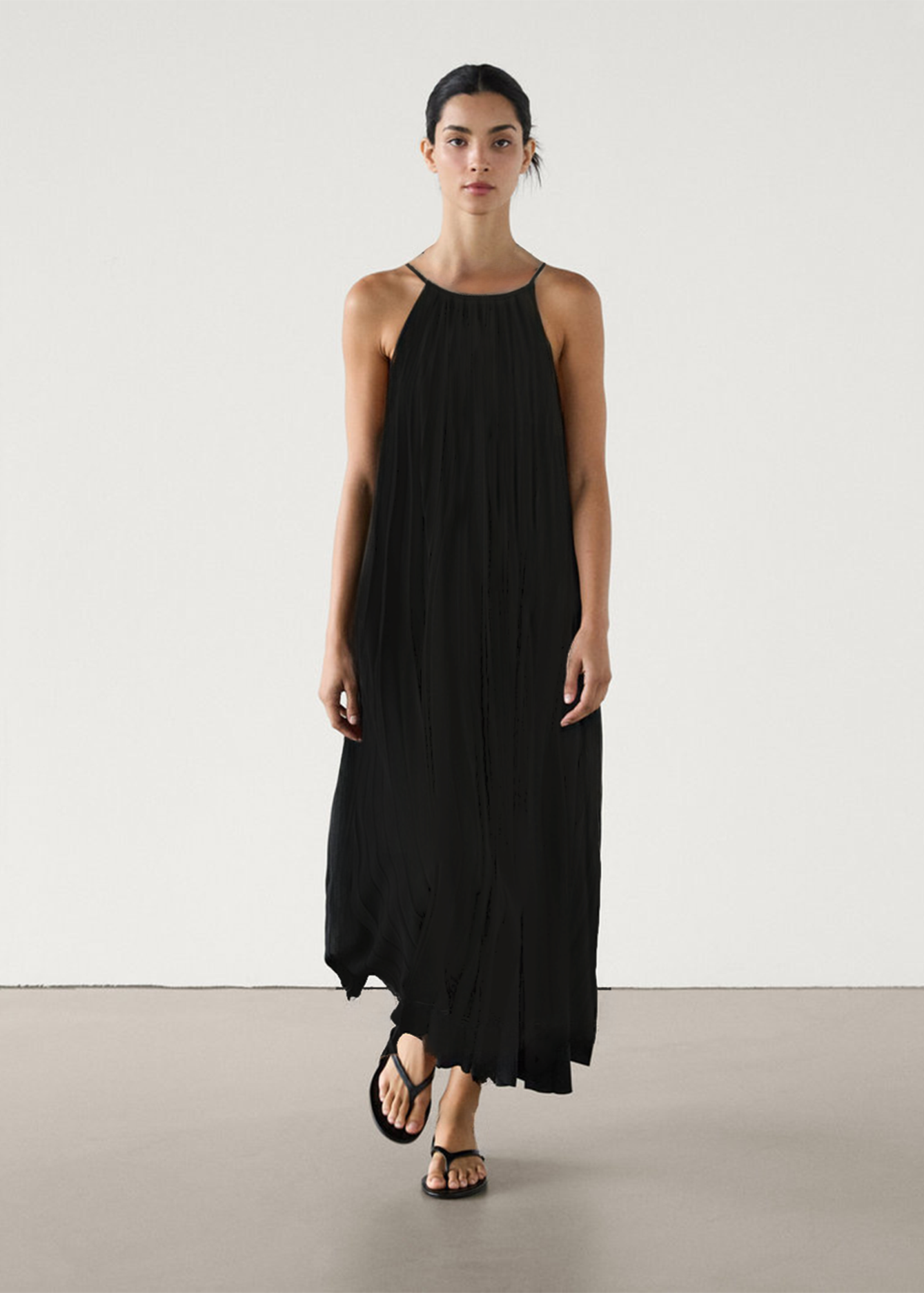 Woman wearing a black halter neck dress on a plain background